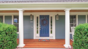 Una casa con puerta azul, columnas blancas y el número 216 en la puerta.