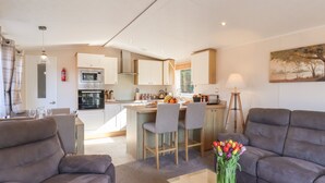 Una sala moderna con un sofá, una mesa de centro con un jarrón de flores, y una zona de cocina con una mesa de comedor.