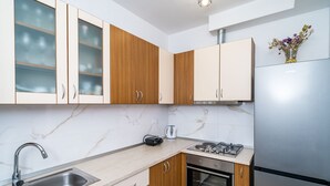 A modern kitchen with wooden cabinets, a stainless steel refrigerator, a built-in oven, and a gas stove. - Apartment N&I - One Bedroom with Terrace (Dubrovnik)