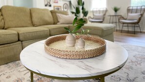 A round table with a woven tray and two vases, a beige sofa, and a chair in a living room. - Coastal Chic Home on the Island of Cape May  (Cape May)