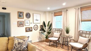 A living room with a sofa, two wicker chairs, a coffee table, and a large plant. - Coastal Chic Home on the Island of Cape May  (Cape May)