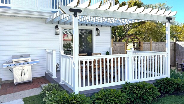 A covered outdoor patio with a grill, white railings, and a pergola. - Coastal Chic Home on the Island of Cape May  (Cape May)