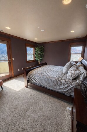 Ein Schlafzimmer mit einem Bett, einer Zimmerpflanze und Bergblick durch die Fenster.