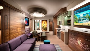 Een moderne hotelkamer met een bank, een eettafel en een kitchenette.