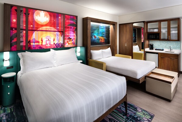 A hotel room with two beds, a small kitchenette, and artwork on the walls.
