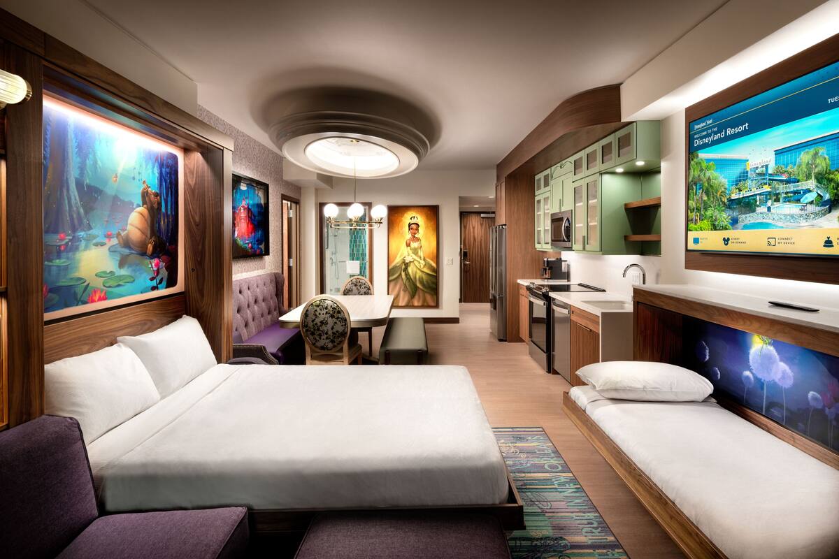 Ein modernes Hotelzimmer mit einem großen Bett, einer Couch, einem Essbereich und einer Küche.