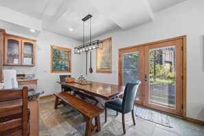 Ein Essbereich mit Holztisch, Stühlen und einer Bank. Es sind Schränke mit Glastüren und eine Deckenleuchte vorhanden.