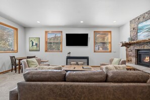 Una sala de estar con chimenea, televisor de pantalla plana y una pared de acento de piedra.