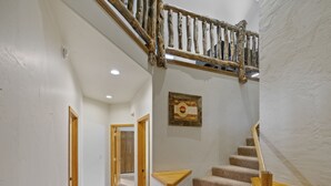Una escalera con barandillas de madera y peldaños alfombrados que sube a un piso superior.