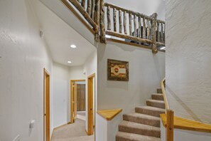 Staircase with a handrail and framed artwork adorns the wall.