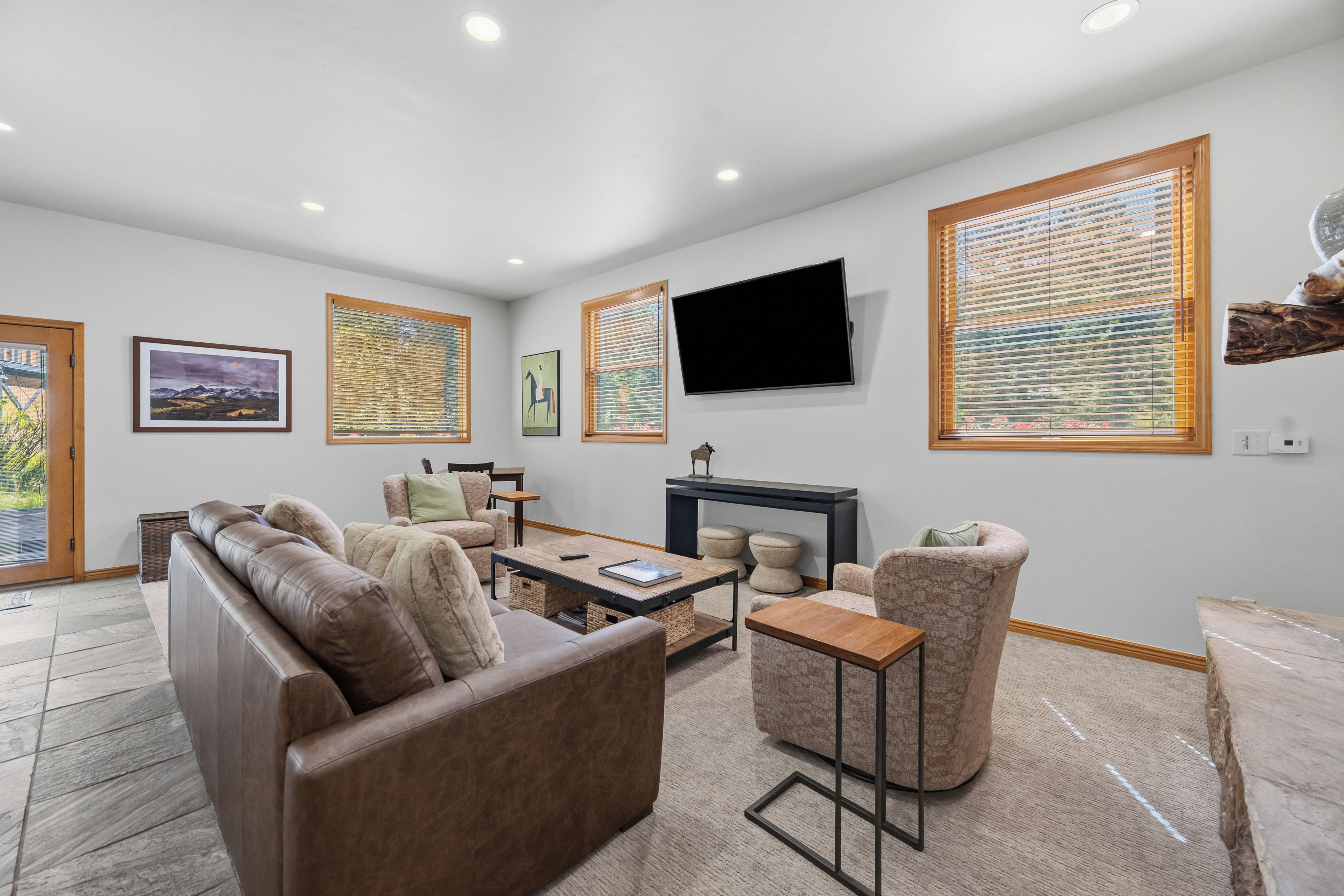 A modern living room with a sofa, armchairs, a coffee table, and a flat-screen TV mounted on the wall.