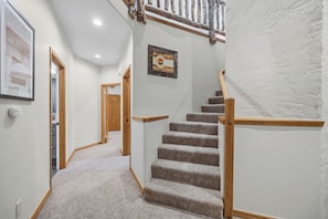 A carpeted staircase with wooden handrails and a wooden door at the bottom.