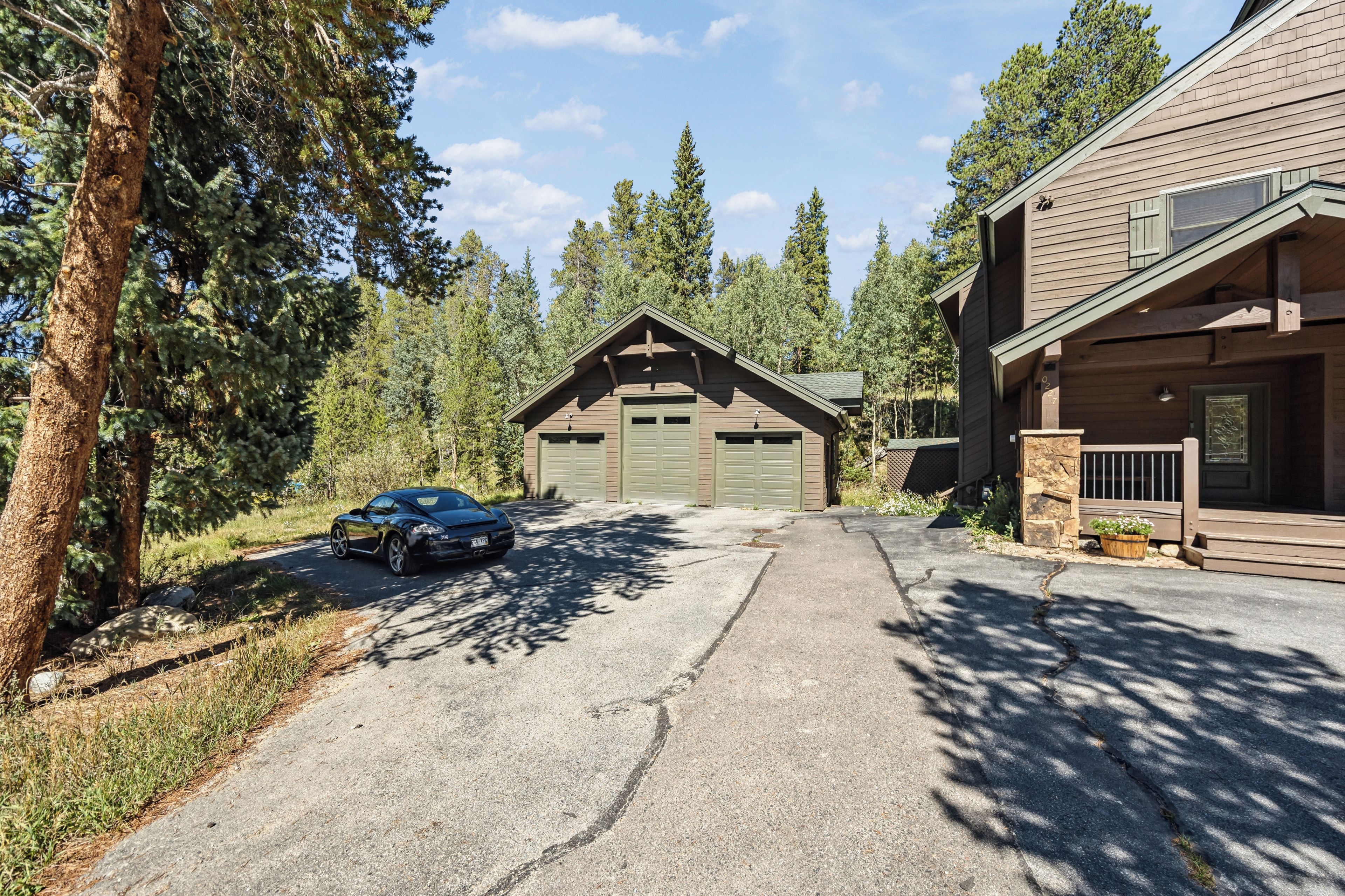 A two-story log cabin with a garage, surrounded by trees.