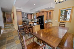 Une cuisine spacieuse dotée de meubles en bois, d’un grand îlot central et d’un coin repas avec une table et des chaises en bois.