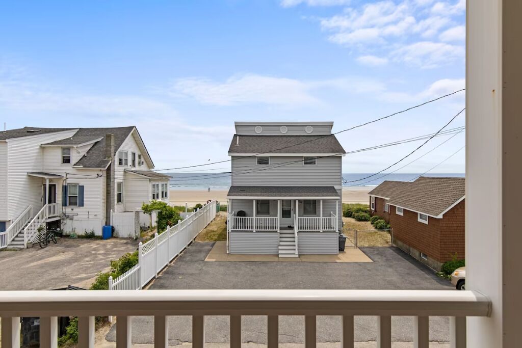 Une zone résidentielle côtière avec des maisons, une plage en arrière-plan et un ciel dégagé.