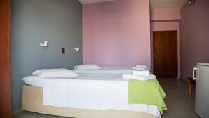 Une chambre d’hôtel avec deux lits, une porte en bois et un petit bureau avec un ordinateur.