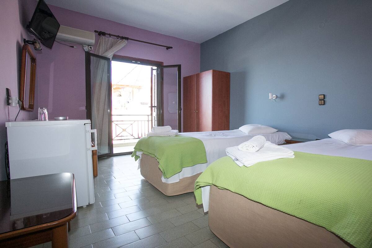Une chambre d’hôtel avec deux lits, un bureau, une télévision et une armoire.