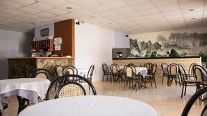 Un restaurant doté d’un comptoir en pierre, de plusieurs tables et de chaises.