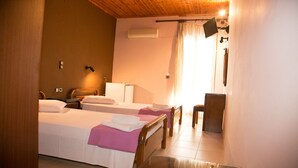Une chambre d’hôtel avec deux lits, un bureau, une chaise, un miroir, une fenêtre avec des rideaux et un appareil de climatisation.