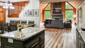 Una cocina moderna con una isla de mármol, suelo de madera y una zona de comedor con sillas y una mesa.