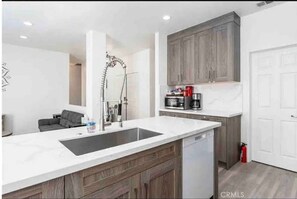 Enjoy cooking in this well-equipped kitchen with a sink, range hood, and convenient appliances.