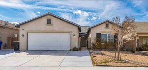 Two single-story houses with attached garages sit in a serene suburban setting.