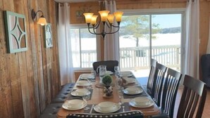 Un coin repas avec une table en bois dressée pour six personnes, entourée de chaises rembourrées.