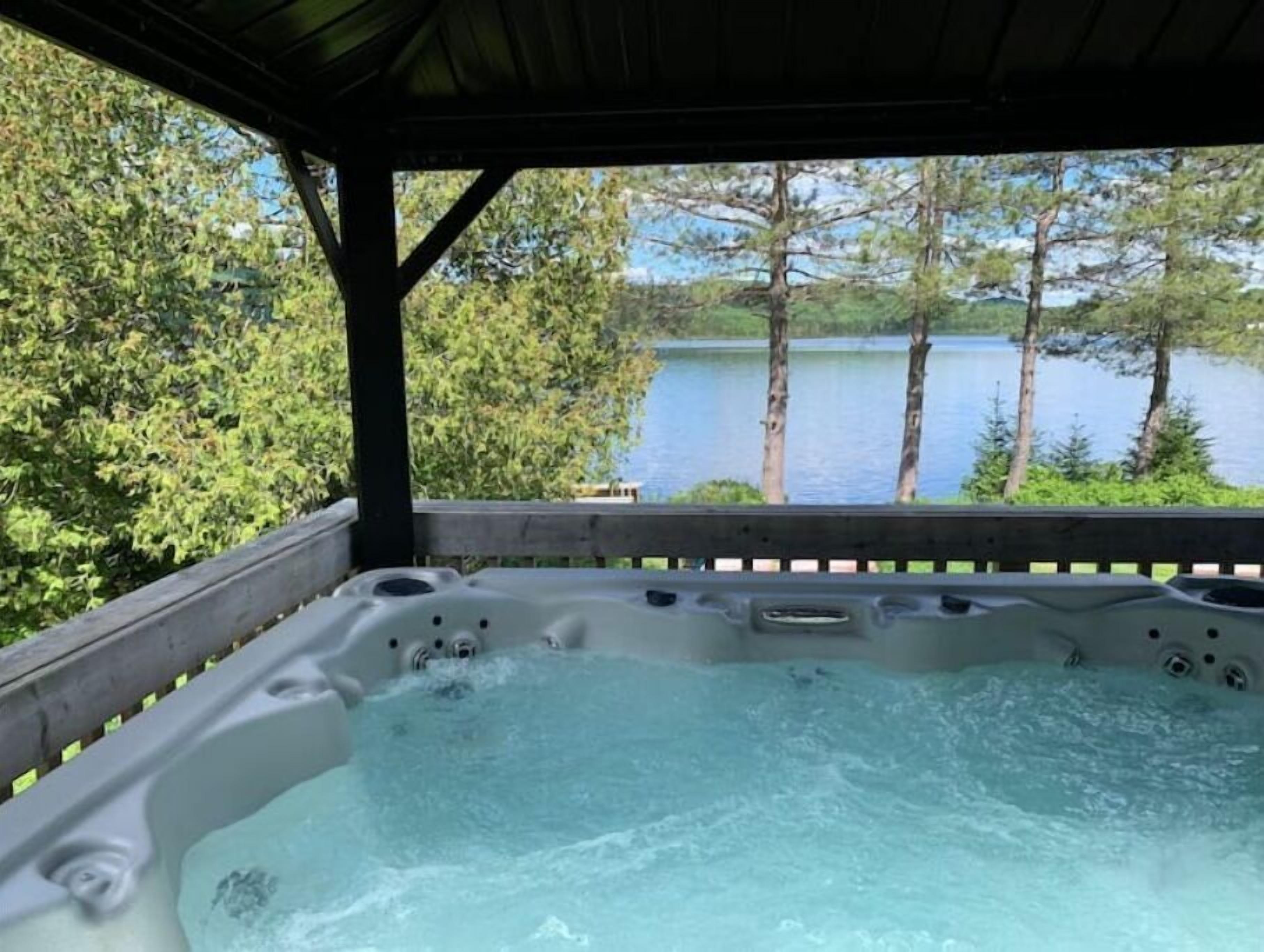 A hot tub with a view of a lake and trees.