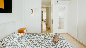 A bedroom with a bed, a door leading to a hallway, and a small window. - Spacious 2 Bedroom Golden Apartment (Callao Salvaje)