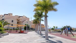 A residential area with apartment buildings, palm trees, and a playground. - Spacious 2 Bedroom Golden Apartment (Callao Salvaje)