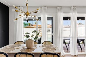 A dining area with a table set for four, a decorative vase, and a modern chandelier. - NEW Heated Pool King bed Tulum inspired Home (Scottsdale)