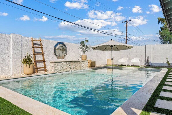 A swimming pool with a stone wall, a wooden ladder, and a potted plant. - NEW Heated Pool King bed Tulum inspired Home (Scottsdale)