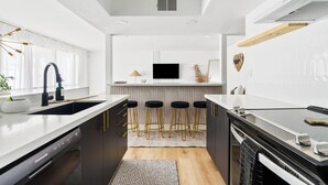 Une cuisine moderne dotée d’un îlot central, de tabourets de bar et d’un four encastré.