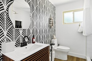A bathroom with a white sink, black faucet, and a mirror. There is a toilet and a window with a curtain. - NEW Heated Pool King bed Tulum inspired Home (Scottsdale)