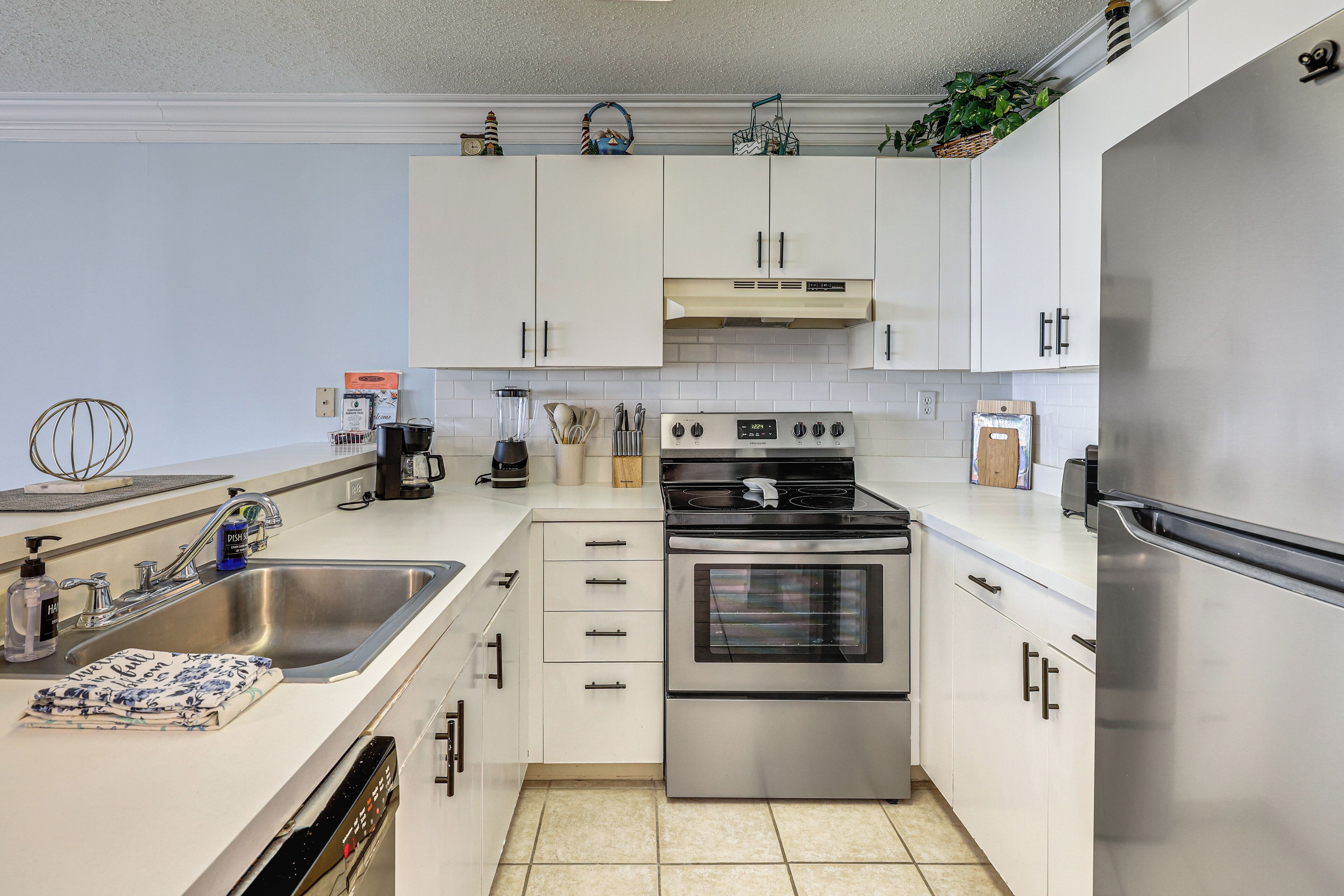 A modern kitchen with white cabinets, stainless steel appliances, a dishwasher, and a sink.