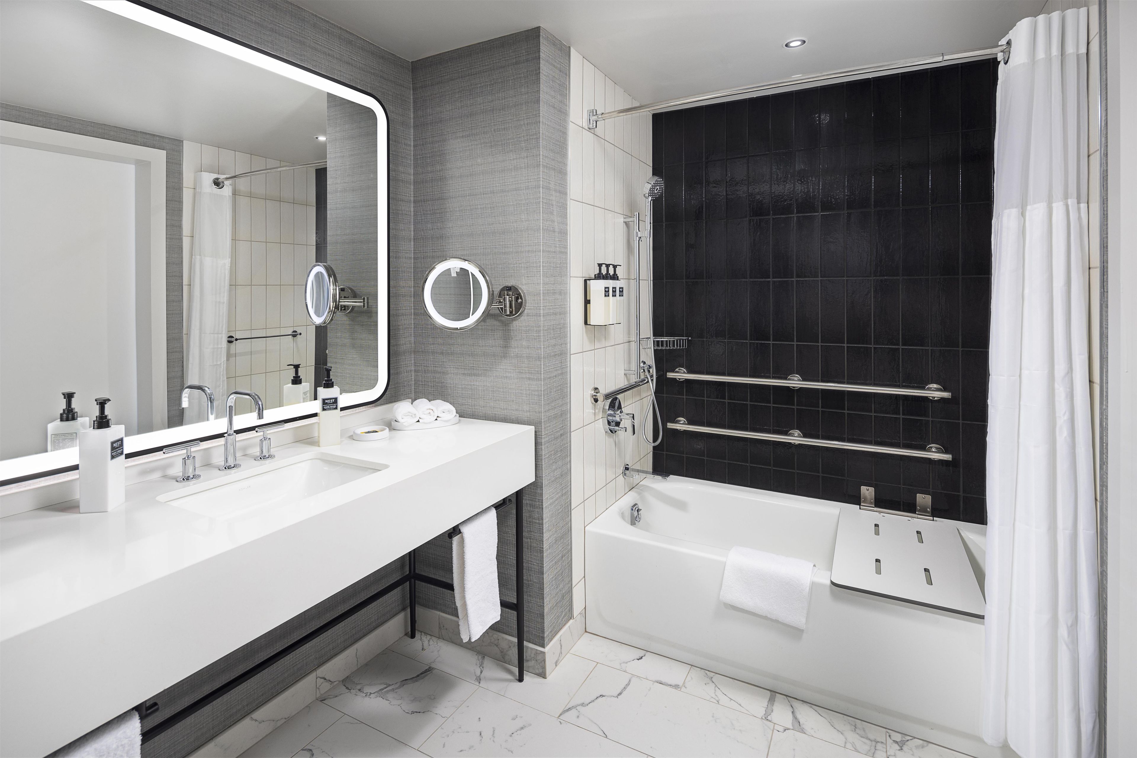 Ein modernes Badezimmer mit einem Waschbecken-Doppelplatz, einem großen Spiegel, einer schwarzen Duschkabine und einer weißen Badewanne.