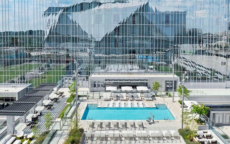 A rooftop pool area with lounge chairs and a swimming pool, surrounded by modern architecture.