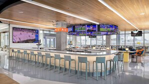 A modern bar area with multiple screens displaying sports events, a curved ceiling, and a bar counter with stools. - Signia By Hilton Atlanta Georgia World Congress Center (Atlanta)