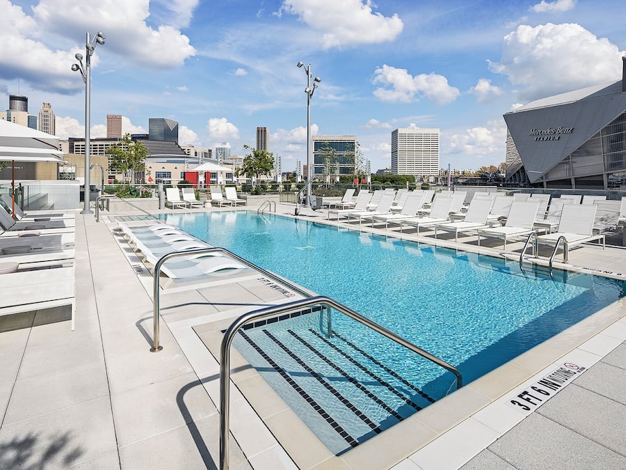 Une piscine avec des chaises longues et une vue sur la ville en arrière-plan.