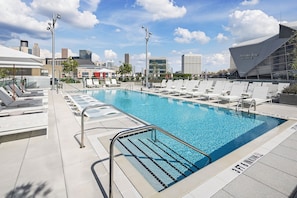 Une piscine avec des chaises longues et une vue sur la ville en arrière-plan.