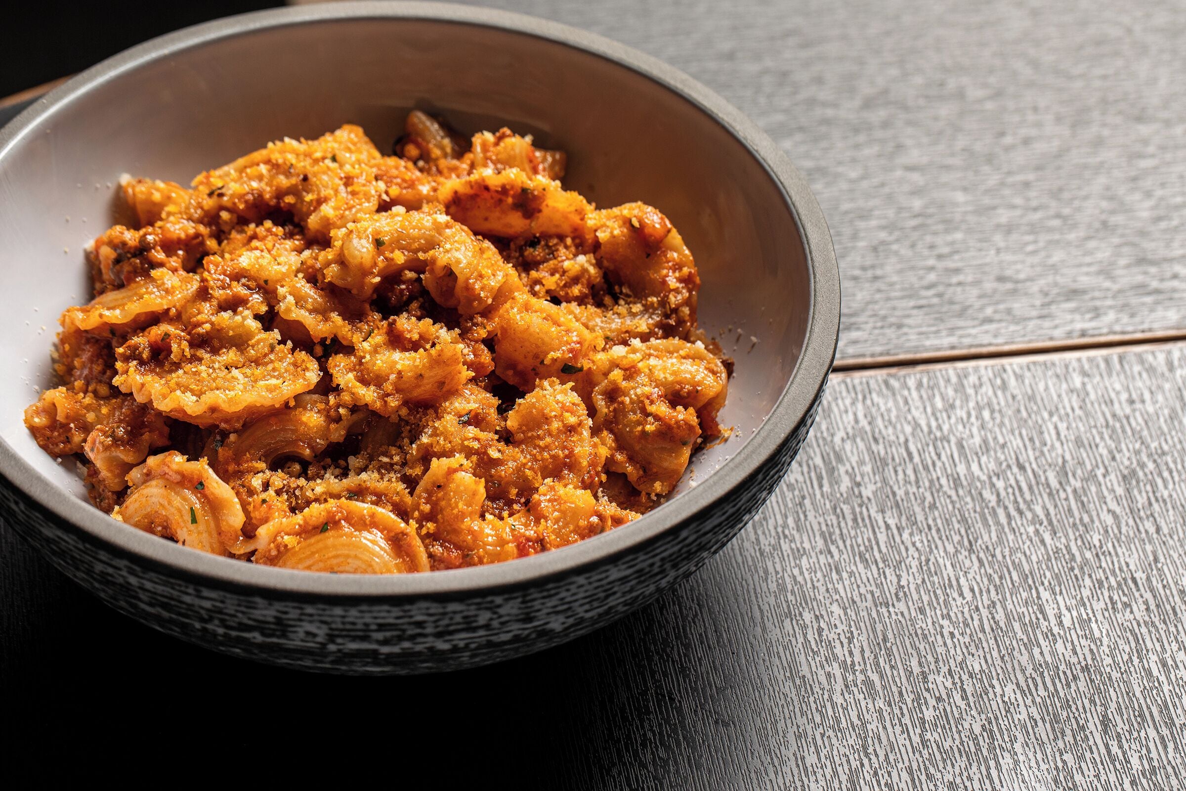 A bowl of food with a textured surface, placed on a dark wooden table.