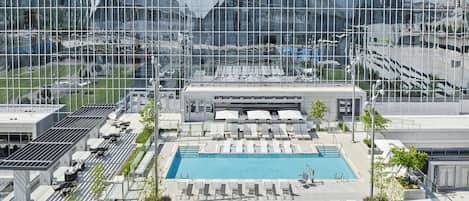 A rooftop pool area with lounge chairs and a swimming pool, surrounded by modern buildings.