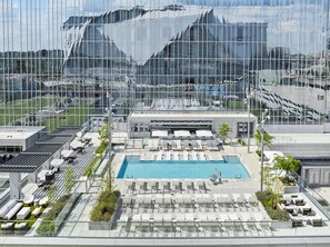 A rooftop pool area with lounge chairs and a swimming pool, surrounded by modern buildings.