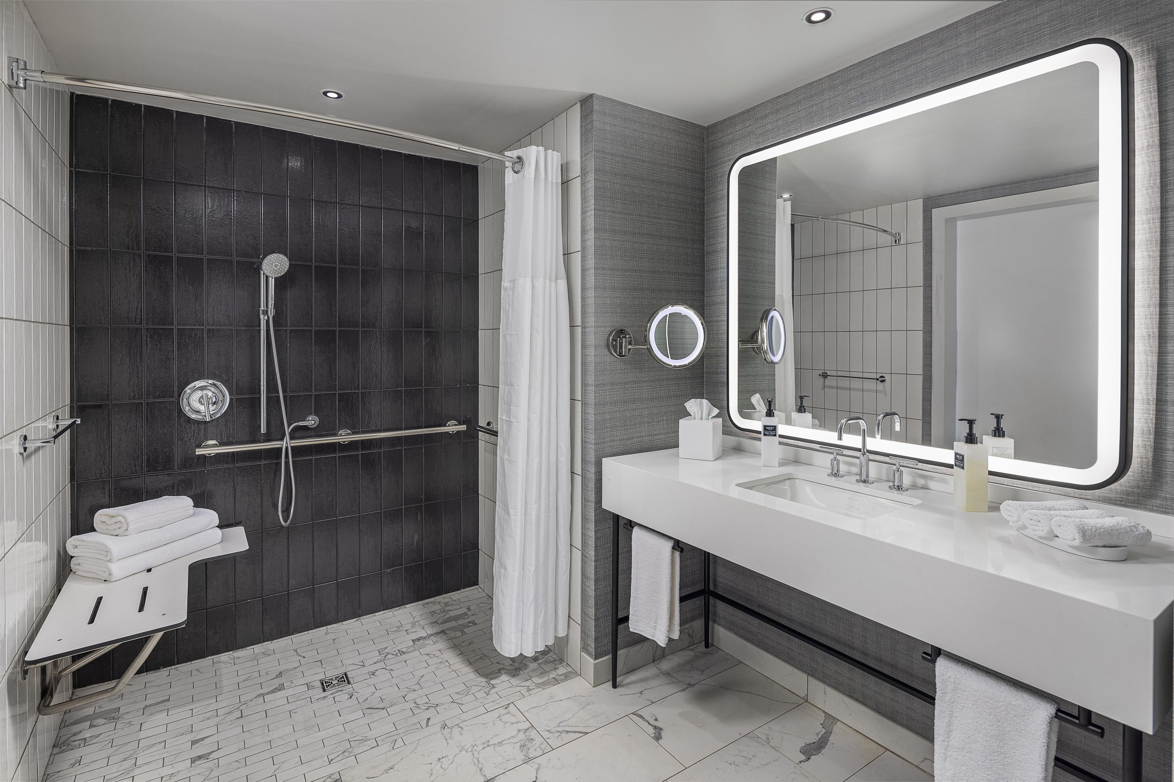 A modern bathroom with a walk-in shower, a large mirror, and a white sink.