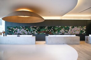 A modern reception area with a large floral wall art, a wooden pendant light, and a minimalist reception desk. - Signia By Hilton Atlanta Georgia World Congress Center (Atlanta)