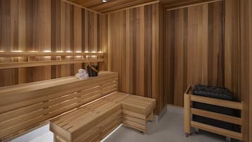 A sauna room with wooden benches and a bench with a black storage box.