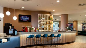 Una zona de bar con un mostrador curvo, taburetes azules y un minibar.