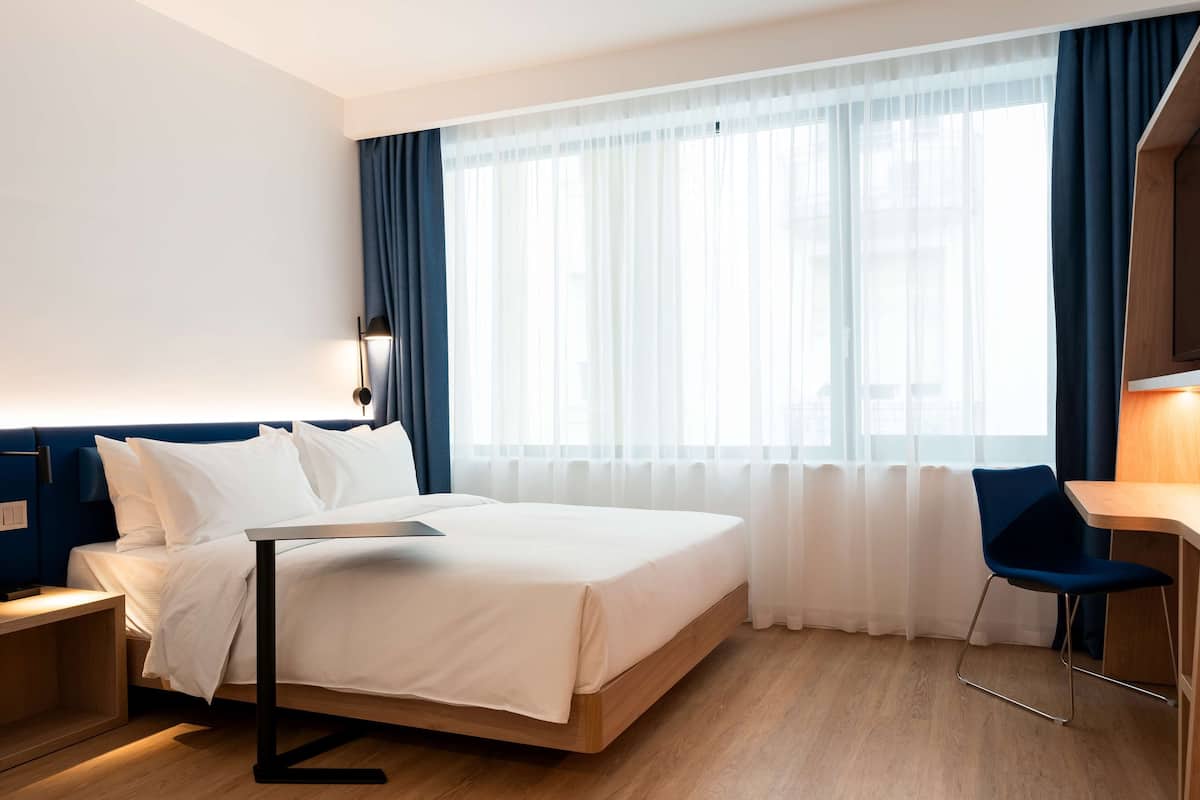 A hotel room with a bed, a desk, and a chair.
