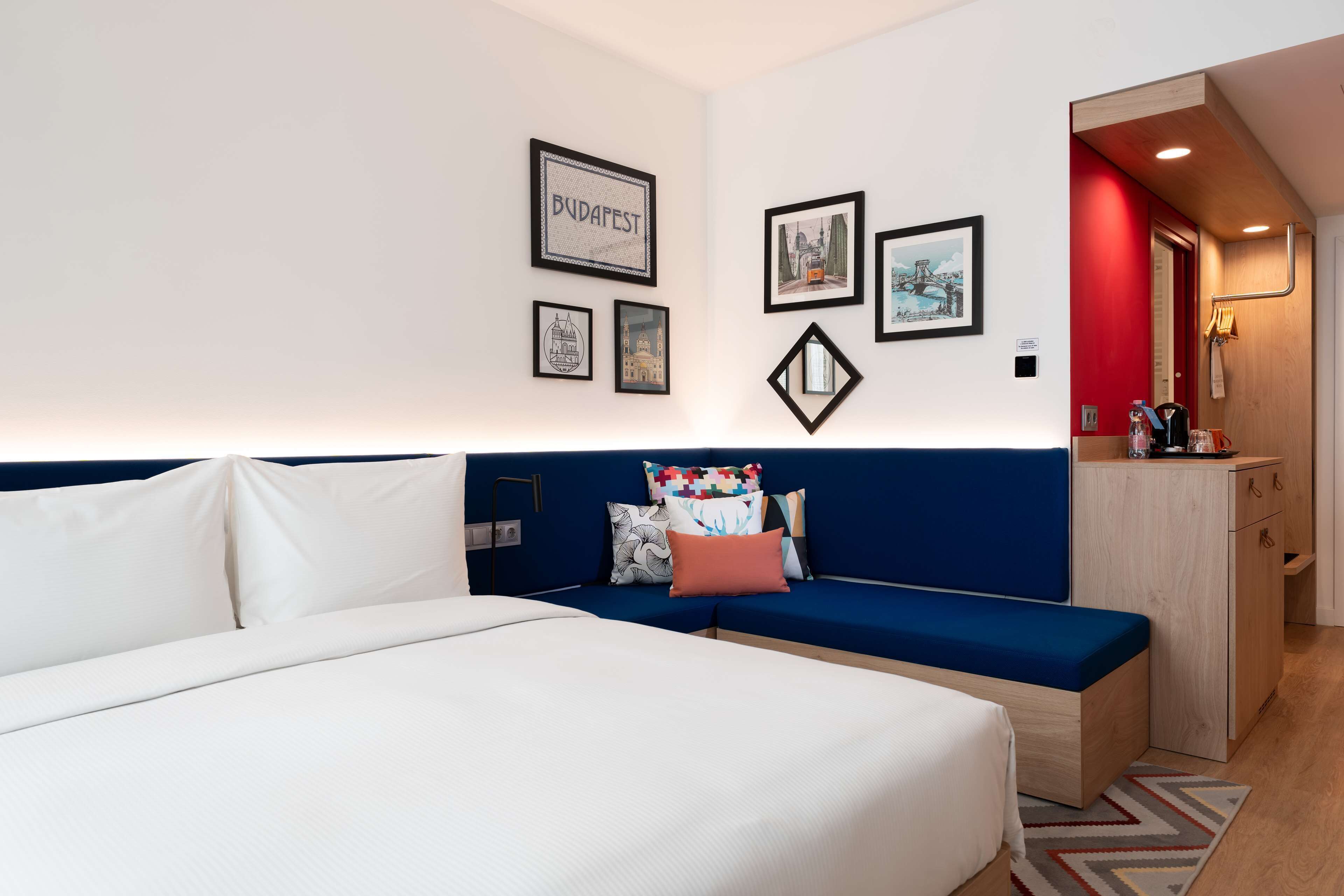 A hotel room with a bed, a blue sofa, and a wooden cabinet.