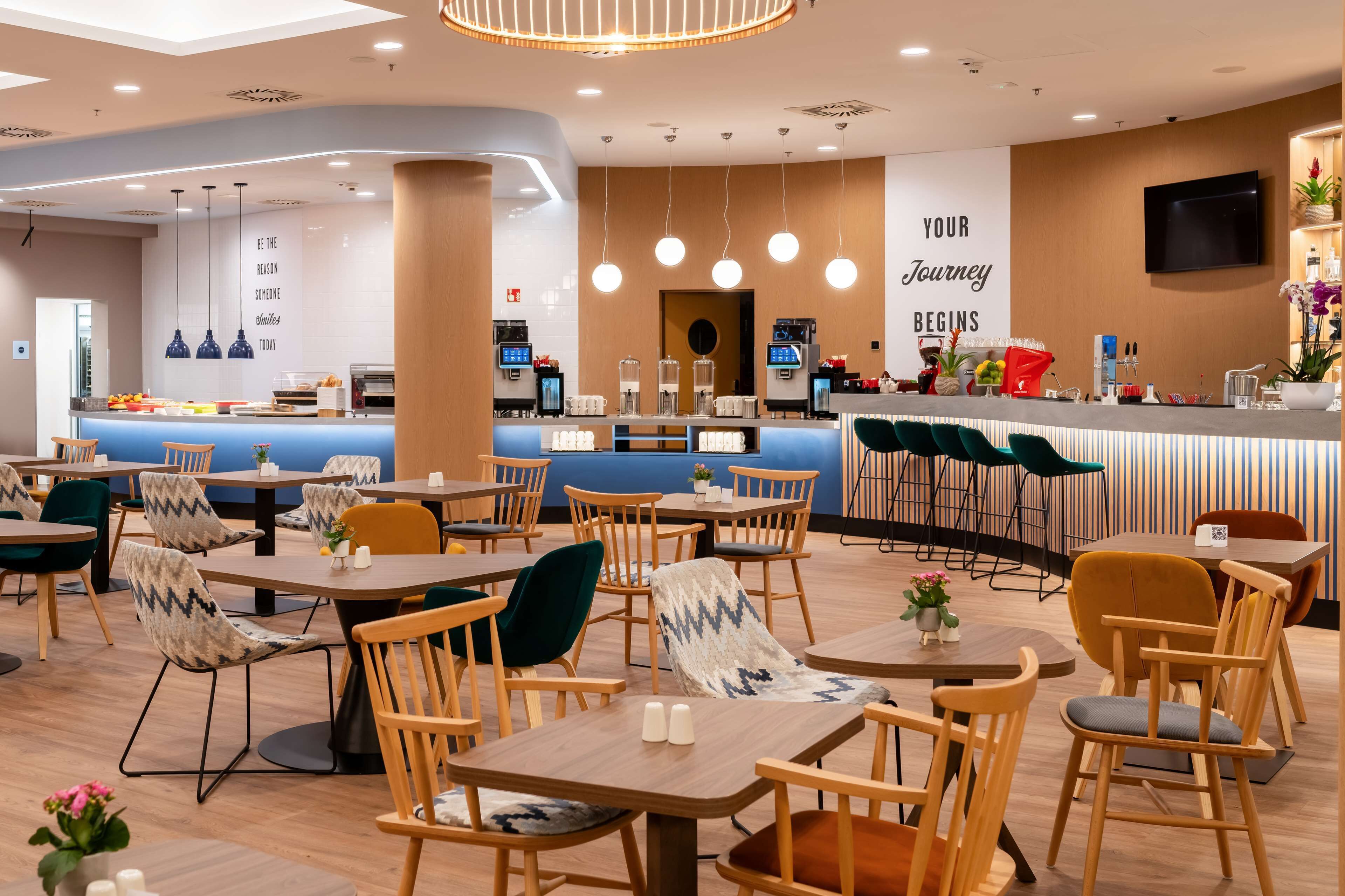 A modern restaurant with a counter, seating area, and a motivational wall.